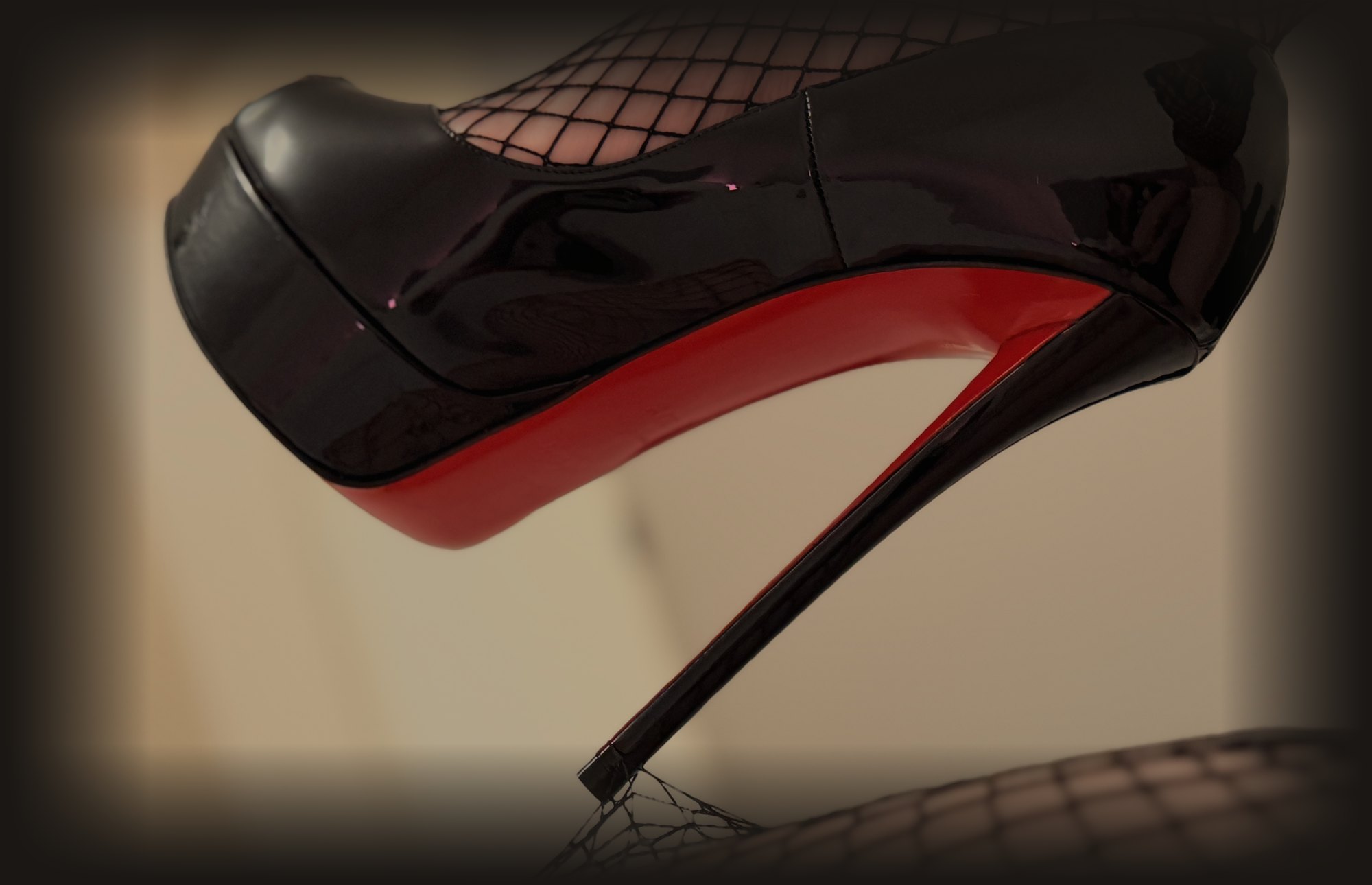 Foot fetish in Sydney: dominatrix Mistress Katya Green's black platform stiletto with red sole resting on a fishnet clad leg