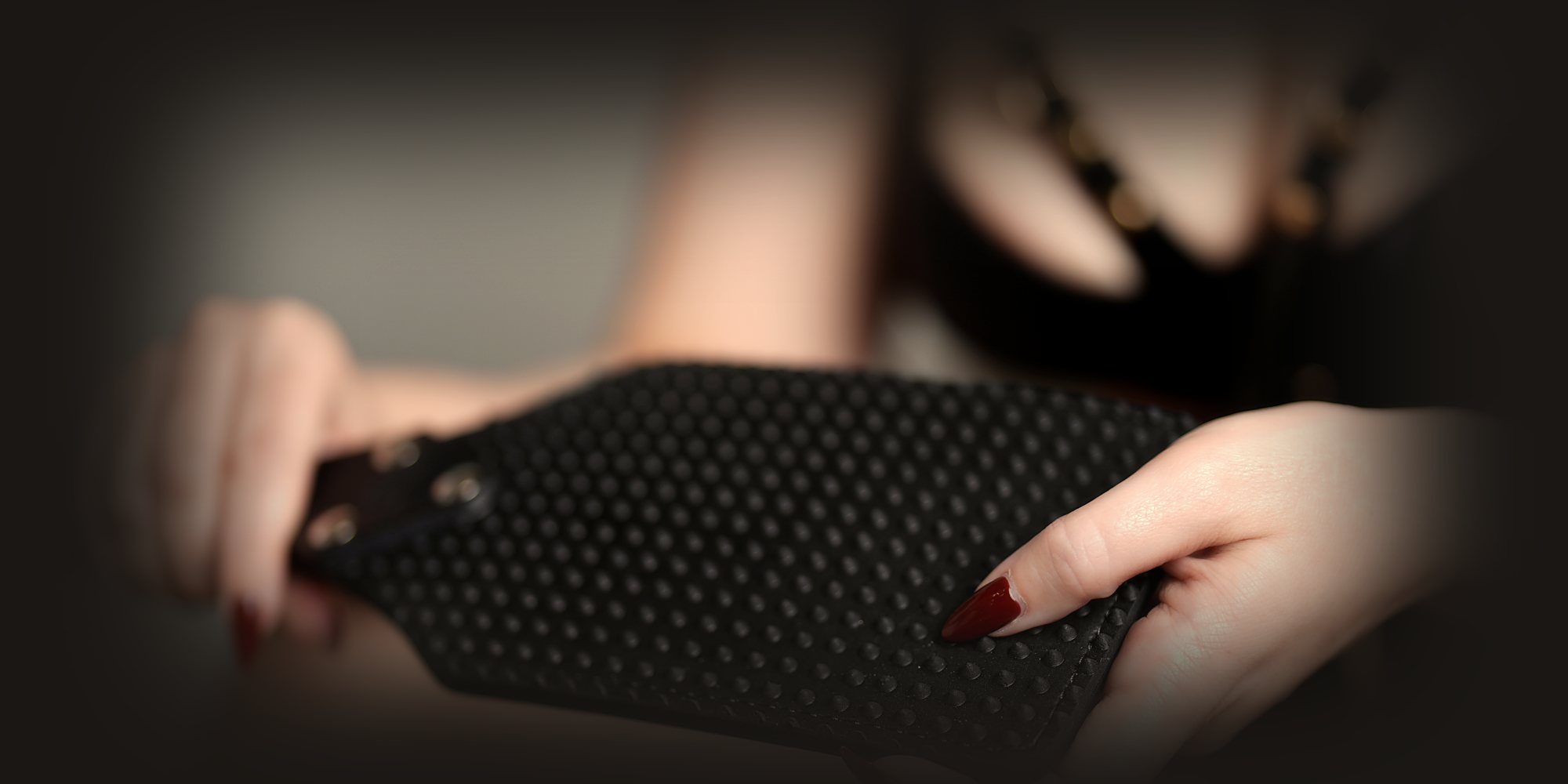 Sydney dominatrix Mistress Katya Green holding a studded spanking paddle, impact play